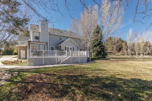 Back of property featuring a chimney, a lawn, and a deck