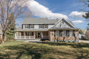 View of front of property featuring a porch, a front lawn, brick siding, and roof with shingles