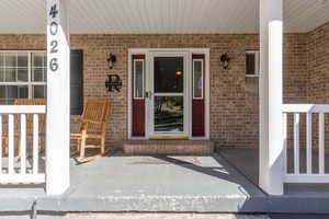 View of exterior entry featuring a porch and brick siding