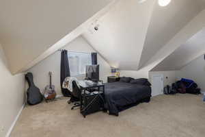 Bedroom with light carpet, vaulted ceiling, and rail lighting
