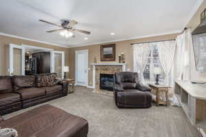 Living room featuring ornamental molding, carpet flooring, ceiling fan, a tile fireplace, and recessed lighting