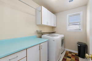 Laundry room with cabinet space, independent washer and dryer, and light tile patterned flooring
