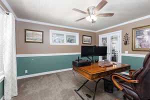 Carpeted home office with french doors, ceiling fan, and crown molding