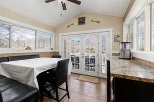 Dining room featuring french doors, wood walls, healthy amount of natural light, light tile patterned floors, and wooden ceiling