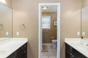 Full bath featuring two vanities and light tile patterned floors