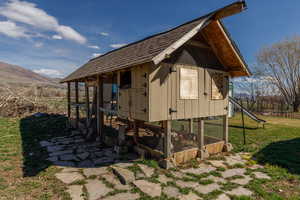 View of side of home with exterior structure, an outdoor structure, a yard, a sunroom, and a mountain view