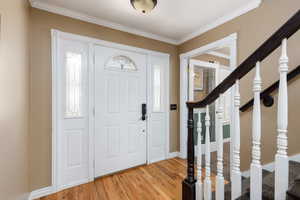 Foyer featuring crown molding and light wood-style flooring