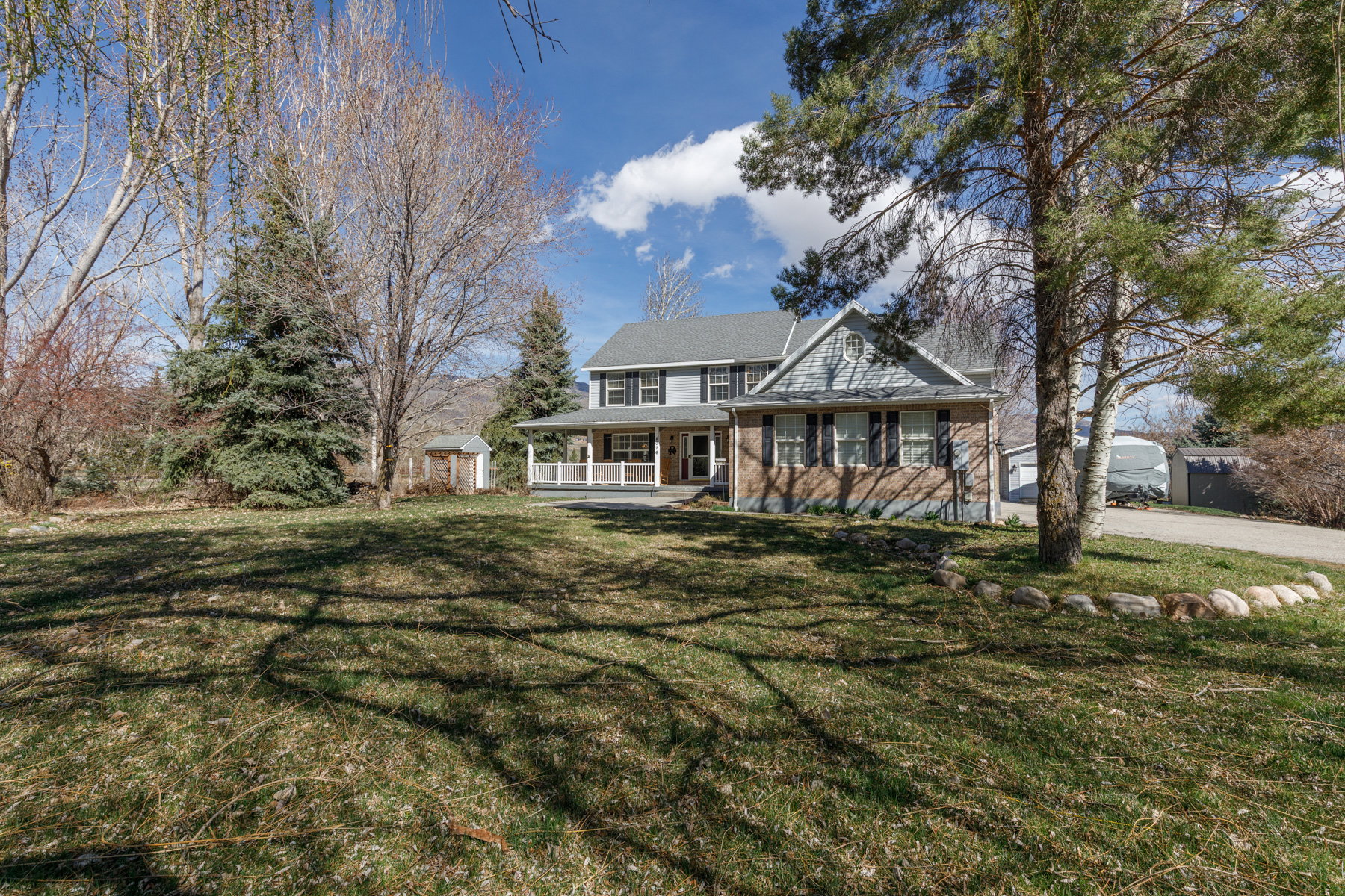 View of front facade featuring covered porch, a storage unit, and a front yard