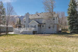 Rear view of property with a chimney, a lawn, and a deck with mountain view