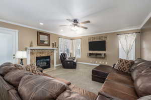 Living area with carpet flooring, a fireplace, crown molding, a ceiling fan, and recessed lighting