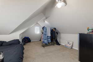 Bedroom featuring freestanding refrigerator, light carpet, vaulted ceiling, a ceiling fan, and track lighting