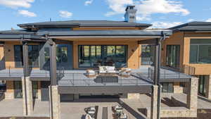 Rear view of property featuring a patio area, a balcony, and a chimney