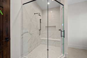 Full bath with a marble finish shower and light tile patterned floors