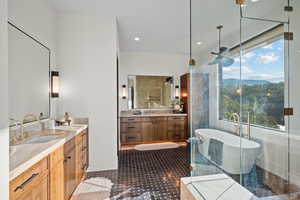 Bathroom with two vanities, a freestanding tub, a mountain view, and recessed lighting
