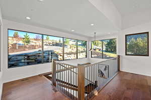 Corridor with an upstairs landing, hardwood / wood-style flooring, and recessed lighting