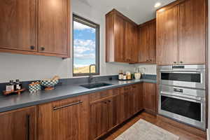Kitchen featuring stainless steel double oven, dark countertops, and wood finish cabinetry