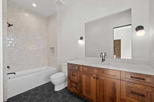 Bathroom featuring vanity, dark tile patterned flooring, shower / tub combination, and recessed lighting