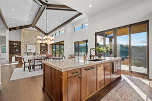 Kitchen featuring a spacious island, dark wood-type flooring, light stone counters, decorative light fixtures, and wood finish cabinetry