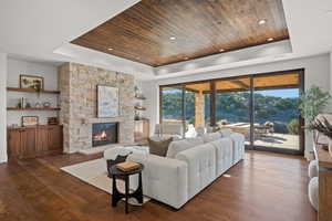 Living area featuring a wooden tray ceiling, dark wood finished floors, and a fireplace