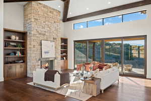 Living room with wood-type flooring, a stone fireplace, recessed lighting, and built in features