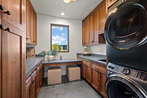 Laundry area featuring cabinet space, stacked washing machine and dryer, and recessed lighting