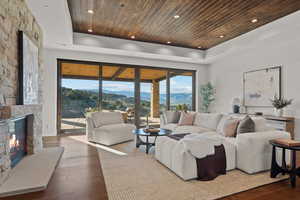 Living area featuring a mountain view, dark wood finished floors, a stone fireplace, and a wood tray ceiling