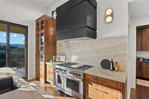 Kitchen featuring double oven range, light stone counters, glass fronted cabinets, and plenty of natural light