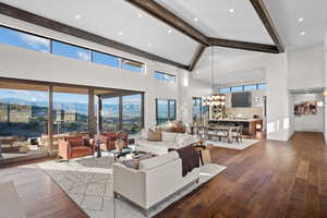Living area with dark wood-type flooring, a mountain view, a chandelier, lofted ceiling, and healthy amount of natural light