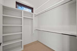 Walk in closet with light colored carpet