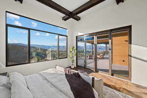 Bedroom featuring a mountain view, access to outside, beam ceiling, and wood finished floors