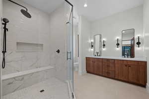 Bathroom featuring double vanity, a marble finish shower, recessed lighting, and light tile patterned floors