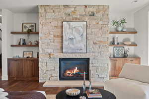 Living room with a stone fireplace and wood finished floors