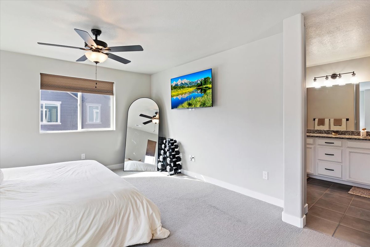 Bedroom featuring dark carpet, ensuite bathroom, a ceiling fan, and dark tile patterned floors