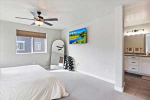 Bedroom featuring dark carpet, ensuite bathroom, a ceiling fan, and dark tile patterned floors