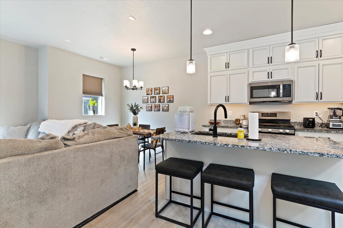 Kitchen with a breakfast bar, light stone counters, white cabinetry, and stainless steel appliances