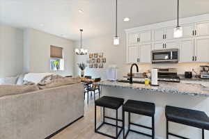 Kitchen with a breakfast bar, light stone counters, white cabinetry, and stainless steel appliances