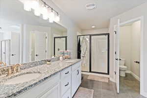 Full bathroom featuring a stall shower, double vanity, and dark tile patterned floors