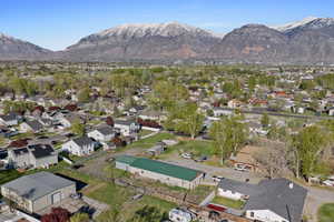 Aerial view of property and surrounding area featuring a mountainous background and nearby suburban area