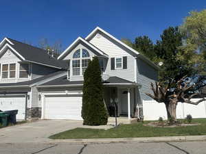 View of front of house featuring driveway, a garage, stone siding, and covered porch