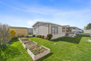 Back exterior with well-maintained lawn, raised garden beds, and outdoor space for gardening or relaxing.