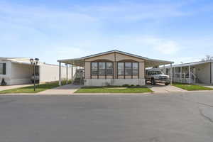 Front view of home featuring a covered carport, extended driveway, and well-maintained landscaping in a quiet community.