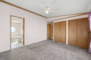 Bedroom with dual closets, ceiling fan, and direct access to en suite bathroom.