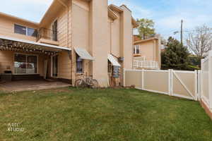 Back of house with a balcony, a chimney, a gate, and a patio