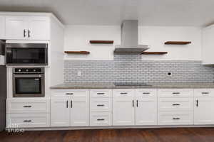 Kitchen with open shelves, exhaust hood, white cabinets, light stone countertops, and stainless steel appliances