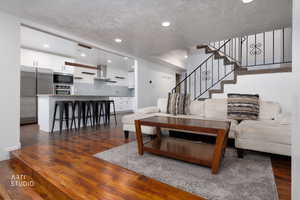 Living room featuring dark wood finished floors, a textured ceiling, and recessed lighting