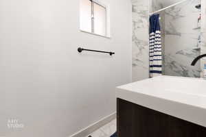 Bathroom with shower / bath combo with shower curtain and light marble finish flooring