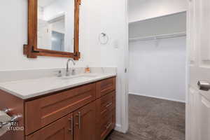 Bathroom with vanity, a spacious closet, and dark carpet