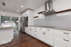 Kitchen with open shelves, light stone countertops, white cabinetry, and stainless steel appliances