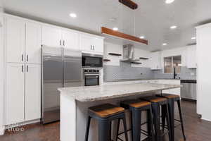 Kitchen with open shelves, a breakfast bar, stainless steel appliances, a center island, and white cabinets