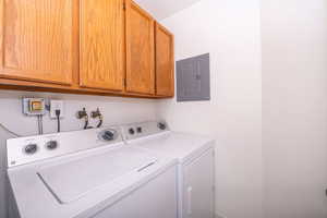 Laundry area with electric panel, cabinet space, and washing machine and dryer